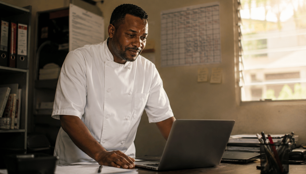 Kingston restaurant owner discovering Claude for Small Business automation on his laptop in his back office, the moment before his operations change permanently.